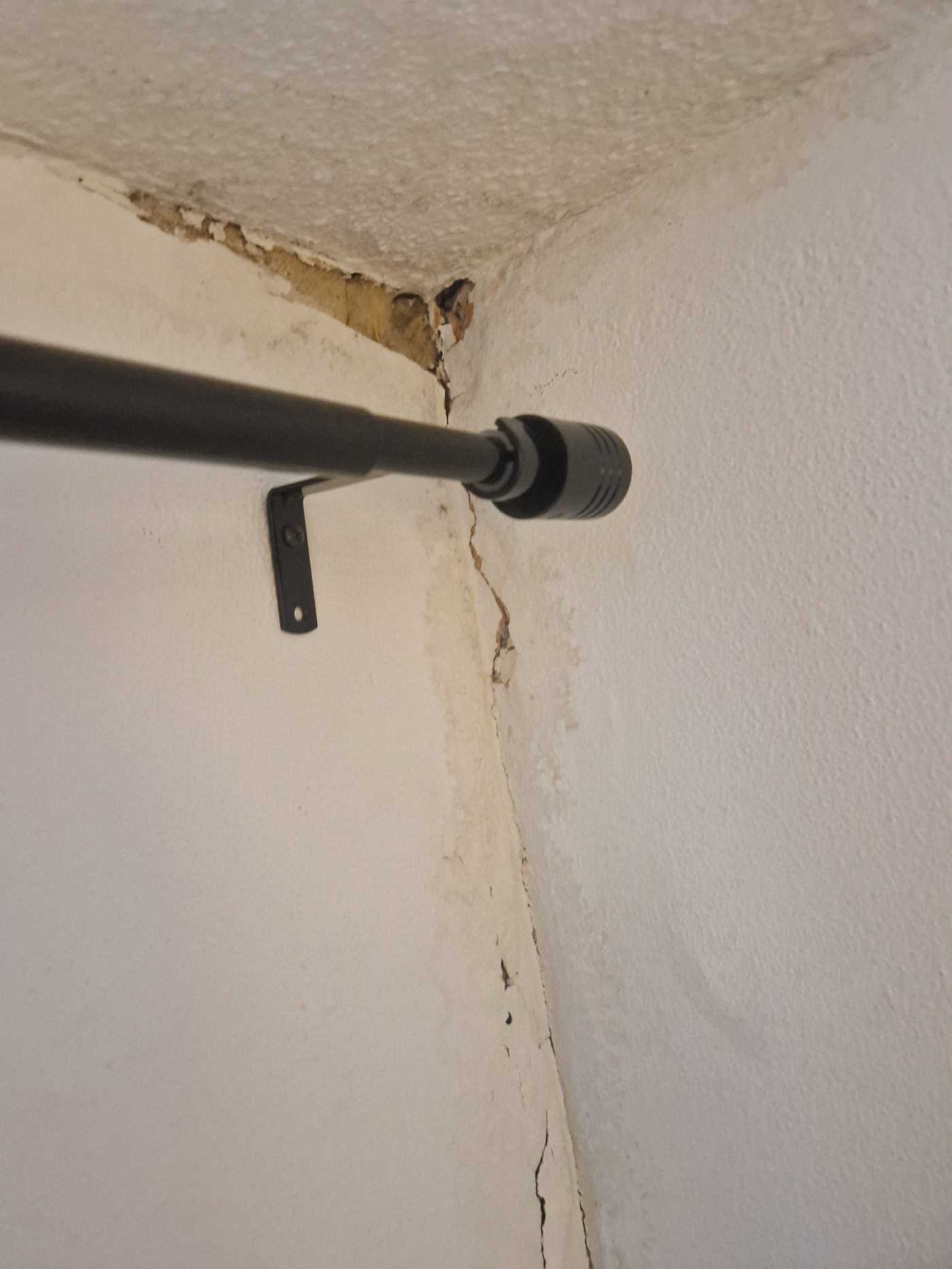 Akoestische lekdetectie met luistermicrofoon bij een beschadigde muur- en plafondhoek met vochtschade