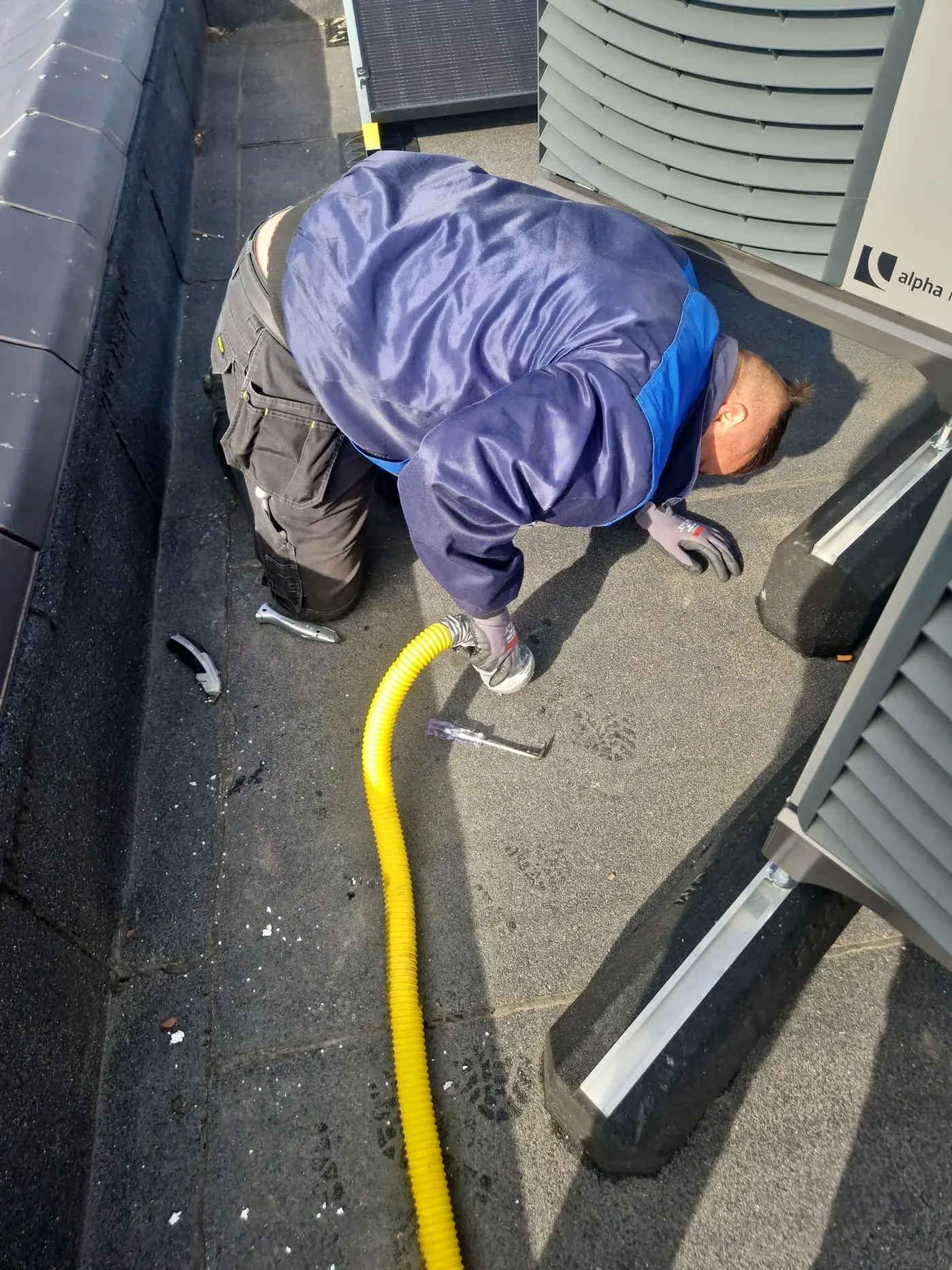 Lekdetectie op een plat dak: technicus voert een rookproef uit bij de dakdoorvoeren en installaties