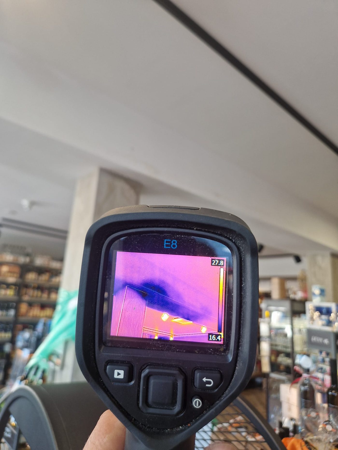 Warmtebeeldcamera toont een koude vochtzone in het plafond van een winkel tijdens lekdetectie in een bedrijfspand